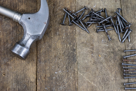 Hammer and nails on a wooden workshop table. Joinery accessories in a DIY workshop. Dark background.の写真素材