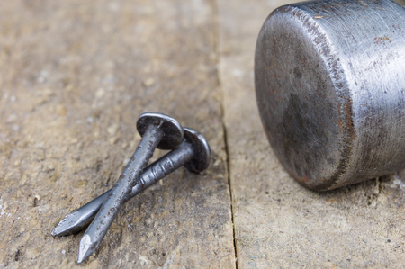 Hammer and nails on a wooden workshop table. Joinery accessories in a DIY workshop. Dark background.の写真素材