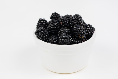 Tasty and ripe blackberries on a white kitchen table. Delicious forest fruits for desserts. White background.の写真素材