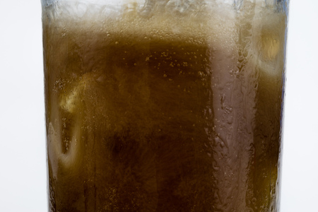 Cold drink with ice in a glass on a white table. A way to cool down on hot days. White background.