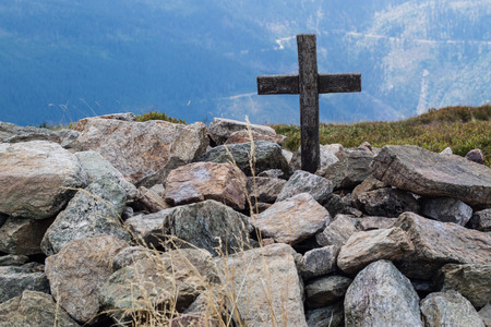 Cross on the top of a mountain in central europe. A wooden sign of Christianity lined with stones. Season of the summer.の写真素材