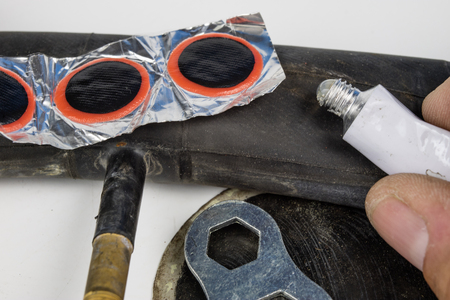 Bicycle tube, glue and patches in the workshop. Repairing a damaged wheel in a bike. Light background.の写真素材