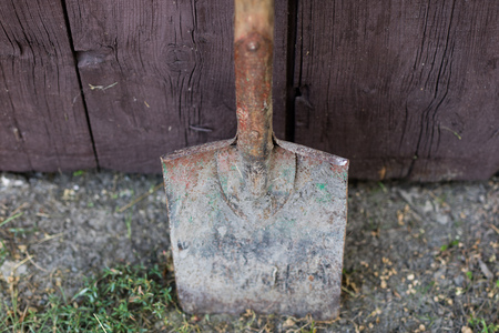 An old garden spade leaning against a wooden door. Tools for working in the field. Season of the...