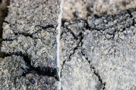 Cracked asphalt on the road for vehicles. Damaged road surface. Season of the summer.
