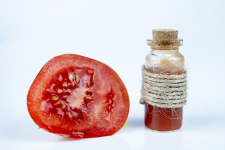 Tasty juice from ripe tomatoes in a small bottle. A healthy and nutritious drink with lots of vitamins. White backgroundの写真素材