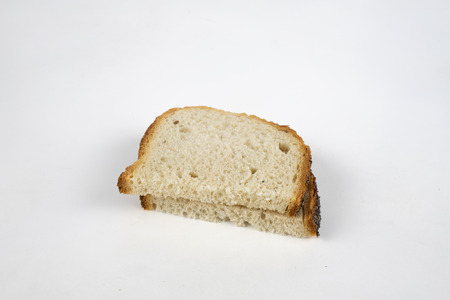 A slice of bread on a white kitchen table. Bread with poppy seeds cut into pieces. White background.の写真素材