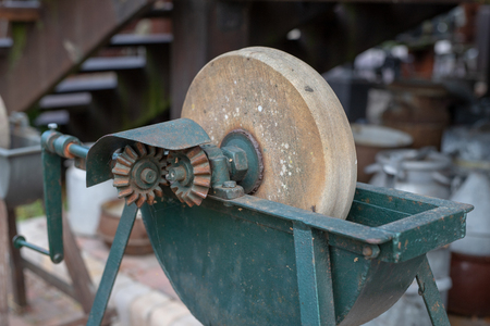 An old whetstone for sharpening knives. Grinding wheel on an old tripod. Season of the autumn.