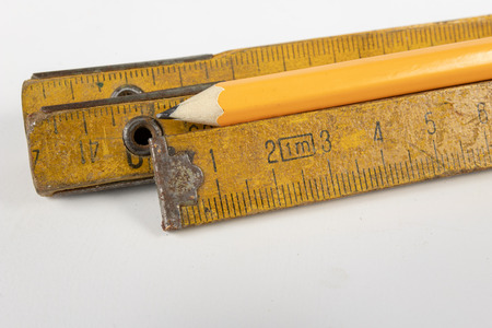 Measure and pencil on a white workshop table. Tools in a carpentry workshop. White background.の写真素材