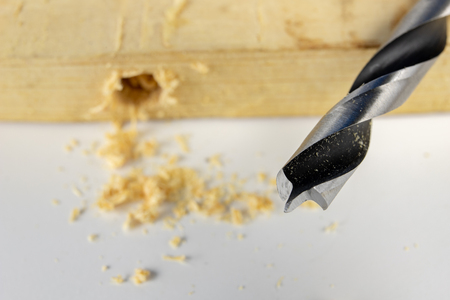 Drilling holes with a wood drill in a workshop. Joinery works performed with the use of cutting tools. White background.の写真素材