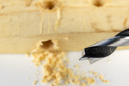 Drilling holes with a wood drill in a workshop. Joinery works performed with the use of cutting tools. White background.の写真素材