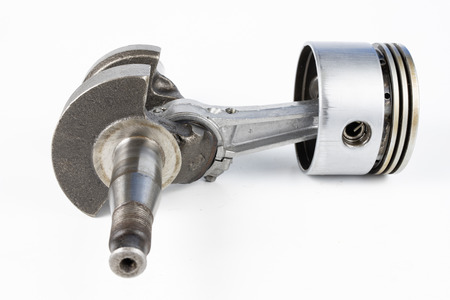 Crankshaft and piston of a small combustion engine on a white table. Spare parts for mechanics. White background.の写真素材