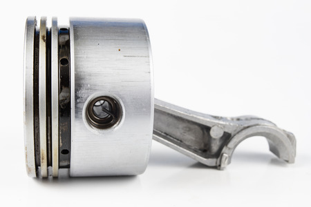A small combustion engine piston on a white table. Spare parts for mechanics. White background.