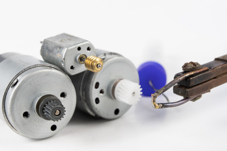 Repair of a small electric motor. Simple soldering work in the electronics workshop. White background.の写真素材