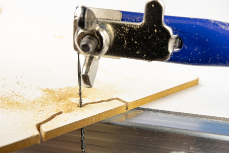 Precise saw for modelers and carpenters on the workshop table. Saw with a small blade for cutting complicated shapes. White background.の写真素材