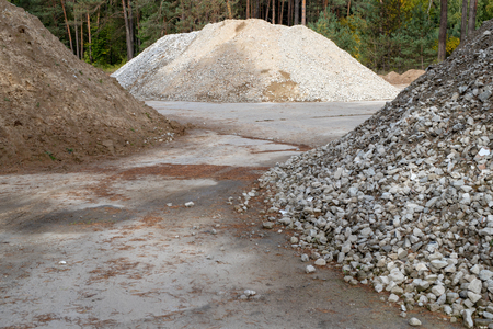 A heap of sand on a concrete square. Count of material for builders in the composition of materials. Season of the autumn.の写真素材
