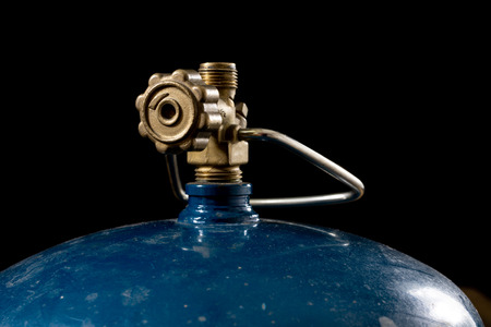 An old gas burner for preparing dishes. Tourist accessories on an old wooden table. Dark background.の写真素材