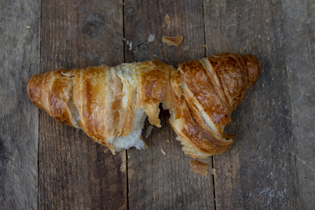 Tasty well-baked croissant on a wooden kitchen table. Light bread prepared for breakfast. Dark background.の写真素材
