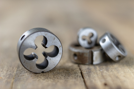 Metalwork tools on the workshop table. Threading dies and taps in an old dusty workshop. Black...