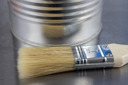 A paint brush and a can of paint on a workshop table. Painting accessories for construction workers. Light background.の写真素材