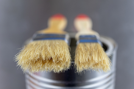 A paint brush and a can of paint on a workshop table. Painting accessories for construction workers. Light background.の写真素材