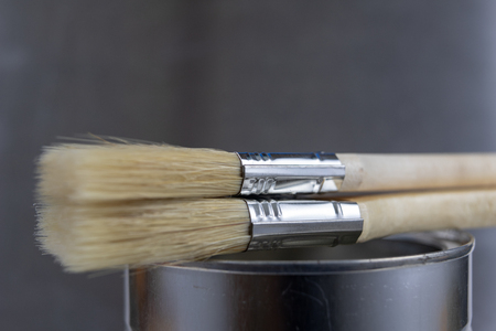 A paint brush and a can of paint on a workshop table. Painting accessories for construction workers....