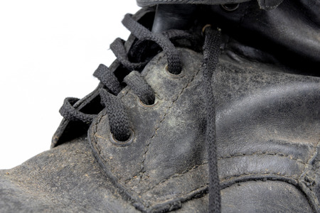 Old black dirty shoes. Leather military footwear on a white table. Light background.