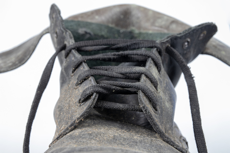 Old black dirty shoes. Leather military footwear on a white table. Light background.