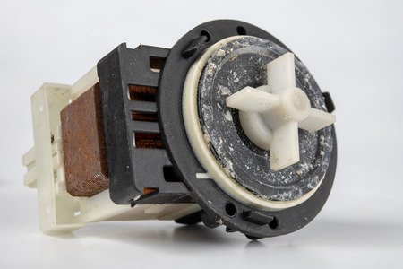 Old washing machine pump. Spare parts for household appliances. Light background.