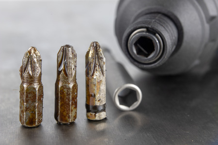 Bits for a screwdriver on a metal workshop table. Workshop accessories for mechanics. Light background.の写真素材