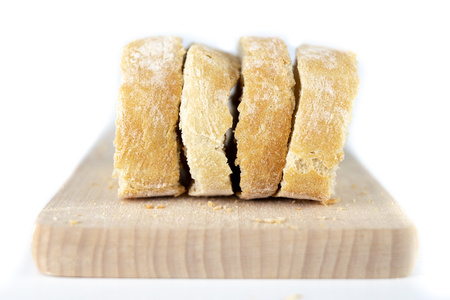 Fresh bread on a wooden kitchen board. A slice of bread smeared with butter. light background.