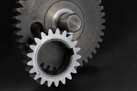 Gears on a metal workshop table. Spare parts for industrial machines. Dark background.