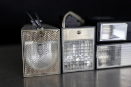 Old flash lamps on a metal table. Photo accessories from central europe. Dark background.の写真素材