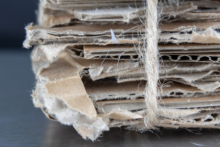 Waste paper bound with a gray cord. Old papers and cardboard intended for recycling. Dark background.の写真素材