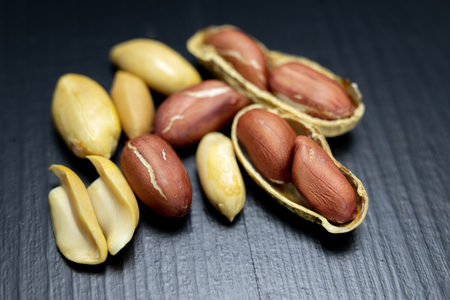Peanuts on a black kitchen table. Tasty ingredients for peanut butter. Dark background.