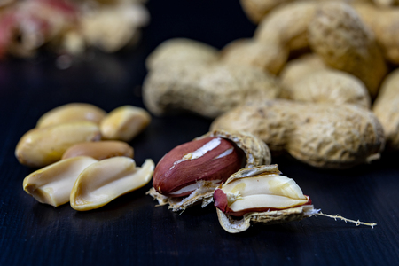 Peanuts on a black kitchen table. Tasty ingredients for peanut butter. Dark background.