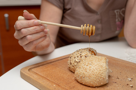 Tasty wheat roll on the kitchen table. Preparing dinner with fresh bread and honey. Autumn background.の写真素材