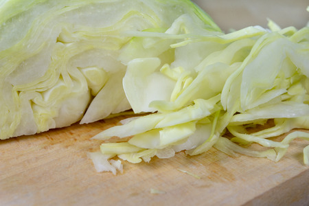 Fresh white cabbage cut into strips on the kitchen table. Vegetables prepared for salad. Light background.の写真素材