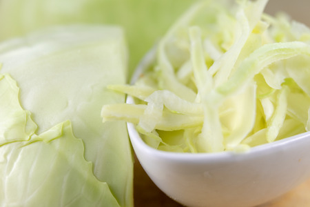 Fresh white cabbage cut into strips on the kitchen table. Vegetables prepared for salad. Light background.の写真素材