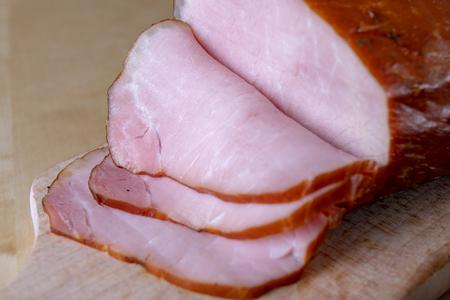 Tasty, fresh smoked pork loin on the kitchen table. Tasty meats prepared for home celebration. Light background.の写真素材