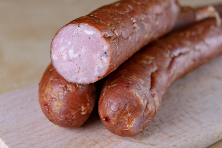 Tasty, fresh sausage smoked on the kitchen table. Tasty meats prepared for home celebration. Light background.の写真素材