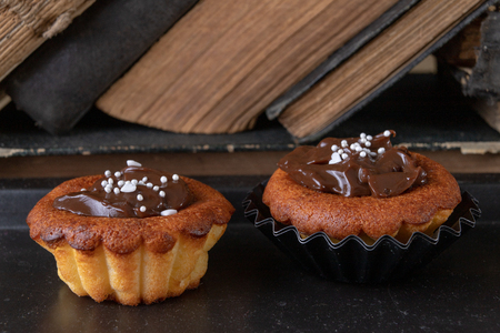 Tasty cupcakes decorated with chocolate and book loss. Dessert on a wooden table in the kitchen. Light background.の写真素材
