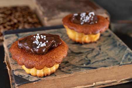 Tasty cupcakes decorated with chocolate and book loss. Dessert on a wooden table in the kitchen. Light background.の写真素材