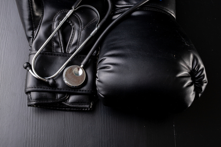Black boxing gloves and a medical stethoscope. Training accessories. Dark background.の写真素材