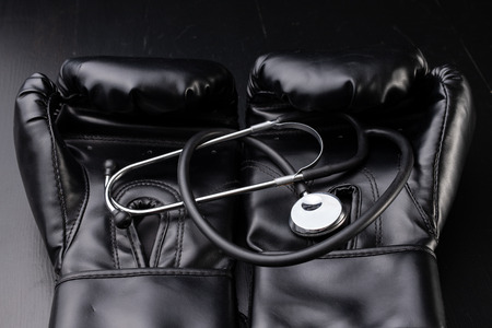 Black boxing gloves and a medical stethoscope. Training accessories. Dark background.の写真素材