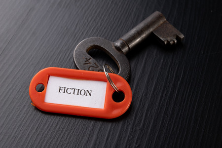 An old key with an inscription on a black table. Accessories and symbol referring to the word in the description of the key. Black background.の写真素材