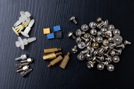 Various screws for assembling computer sets. Accessories for mechanic electronics. Dark background.