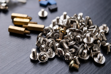 Various screws for assembling computer sets. Accessories for mechanic electronics. Dark background.