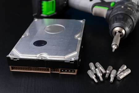 Repair and diagnostics of hard disk. Service of computer parts in the workshop. Dark background.