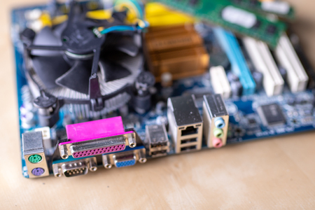 The motherboard and computer components. Computer accessories on a workshop table. Dark background.