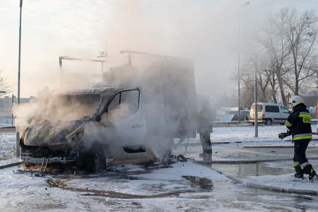 Car fire at the gas station in Orlen, Poland. Burning van and firefighters extinguishing a fire. Season - winter.のeditorial素材